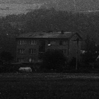 Rural landscape with misty mountains and farmhouses.