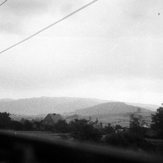 Rural landscape with hills, house, and power lines.