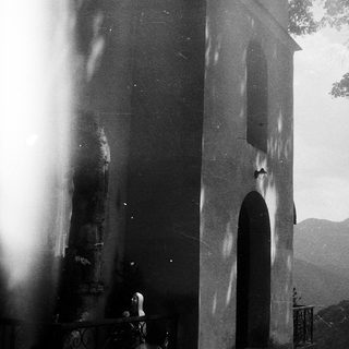 "Black-and-white view of a bell tower with distant mountains."