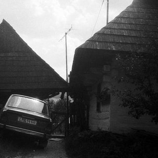 Traditional wooden houses with steep roofs, parked car.