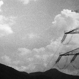 Dramatic clouds over mountainous landscape with power lines.