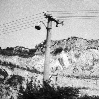 Rural landscape with power lines and rocky hillside.