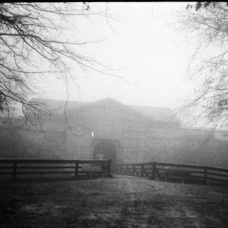 Misty landscape with foggy path and distant building.