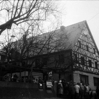 Traditional half-timbered building with people gathered outside.