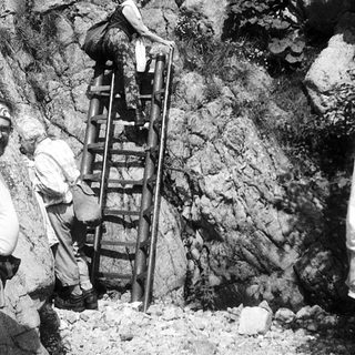 People climbing rocky terrain using ladders.