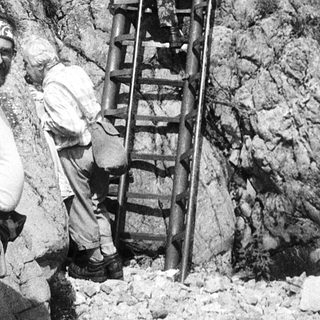 People climbing rocky terrain using ladders.