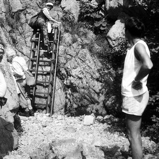 People climbing rocky terrain using ladders.
