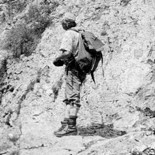 Soldiers climbing rugged mountain terrain.