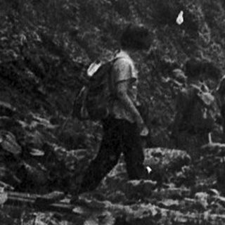 Steep mountain gorge with narrow path and hikers.
