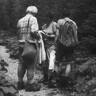Two hikers carrying backpacks on a rocky trail.