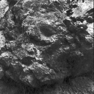 Rough, textured rock surface with mineral deposits.