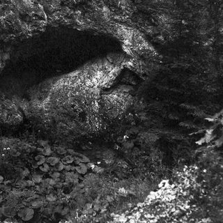 Dark cave interior with mineral deposits and water flow.
