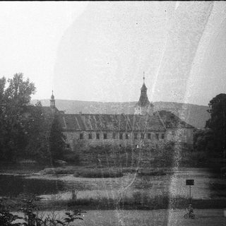 Historic castle by serene lake surrounded by trees.