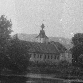 Scenic view of historic building by river with trees.