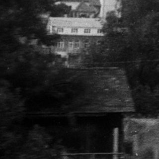 Rural scene with house nestled in forested hills.