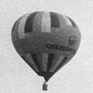 Hot air balloon over urban river scene.