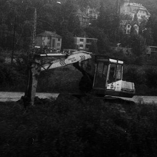 Construction site with excavator on hilly terrain.