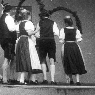 Traditional folk dancers in regional costumes performing on stage.