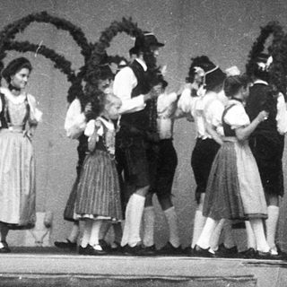 Traditional folk dancers in regional costumes performing on stage.