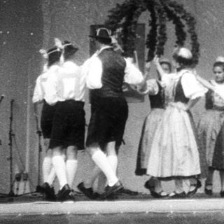 Traditional folk dancers in regional costumes on stage.
