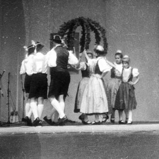 Traditional folk dancers in regional costumes on stage.