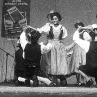 Group performing dance routine on stage with live band.
