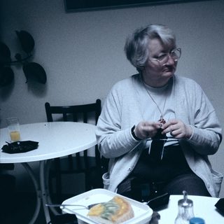 Person eating lunch while crocheting indoors.