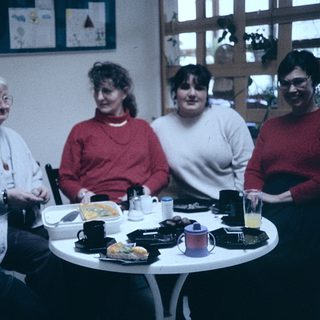 Group of five women sitting together indoors at a meal.