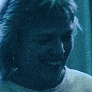 Three people crafting together indoors with paper.