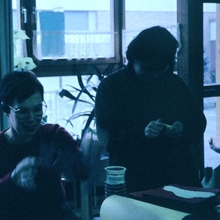 Three people crafting together indoors with paper.