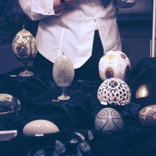 Elegant decorative eggs and ornate stands displayed.