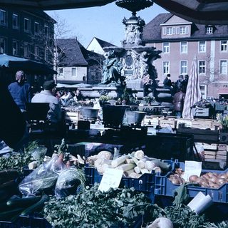 Outdoor market with fresh produce and people shopping.