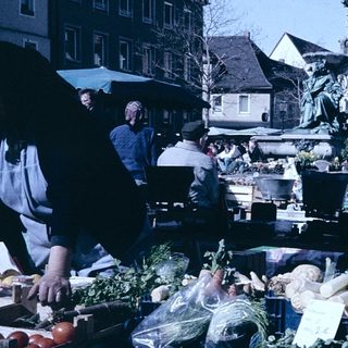 Outdoor market with fresh produce and people shopping.