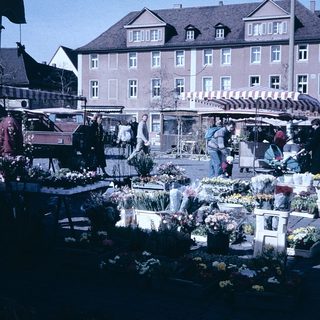 Outdoor flower market with stalls and people.