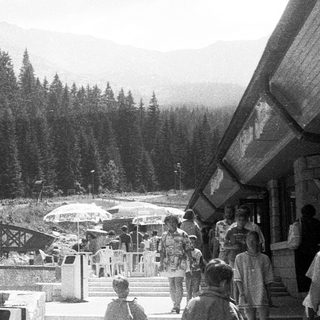 Scenic mountain resort area with bridge, forest, and visitors.