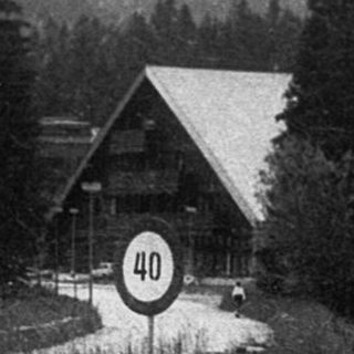 Mountain pass entrance with lodge and forested hills.