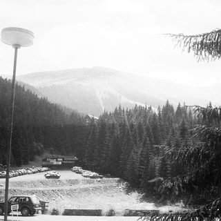 Snowy mountain resort parking area with forested slopes.