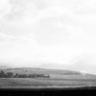 Rural landscape with distant hills and cloudy sky.