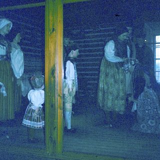 Historical figures in traditional 19th-century attire indoors.