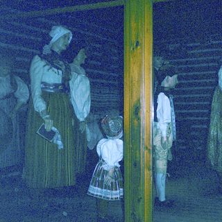 Historical figures in traditional 19th-century attire indoors.