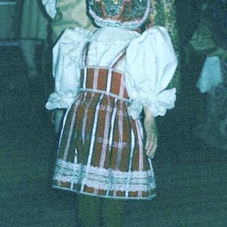 Traditional folk costumes in a dimly lit indoor gathering.