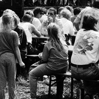 Outdoor concert or event with crowd seated on benches.