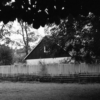Historic building surrounded by old fence and trees.