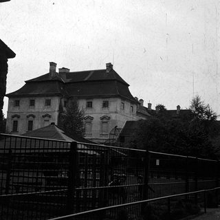 Large historic building behind metal fence.