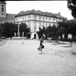 Historic European city square with grand building and statue.