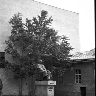 Statue of seated historical figure in park setting.