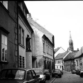 Historic European street with parked cars and old architecture.
