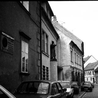 Historic European street with parked cars and old architecture.