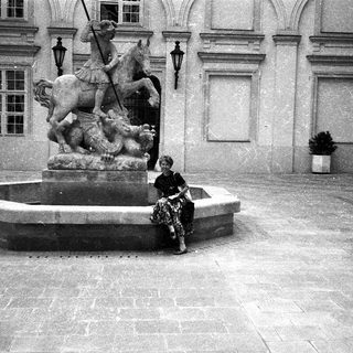 A person sitting on a historic fountain featuring a knight statue.