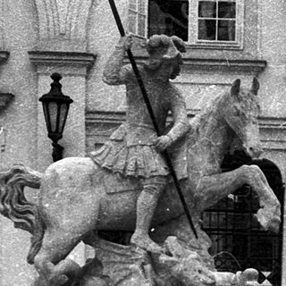 A person sitting on a historic fountain featuring a knight statue.